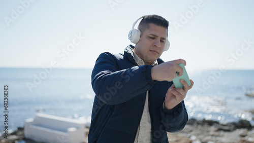 Young hispanic man playing video game at seaside photo