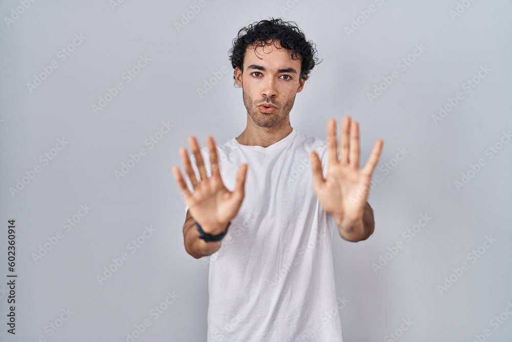 Naklejka premium Hispanic man standing over isolated background moving away hands palms showing refusal and denial with afraid and disgusting expression. stop and forbidden.