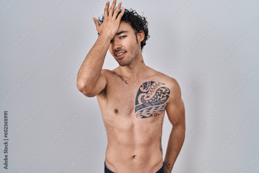 Fototapeta premium Hispanic man standing shirtless surprised with hand on head for mistake, remember error. forgot, bad memory concept.