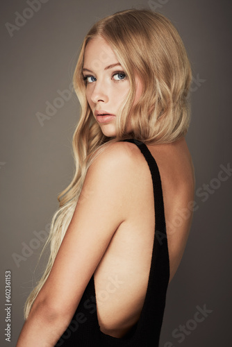Seductive, face and beauty portrait of a woman with makeup, cosmetics and long hair in studio. Headshot of a female aesthetic model with a skin glow, luxury skincare and fashion on a grey background