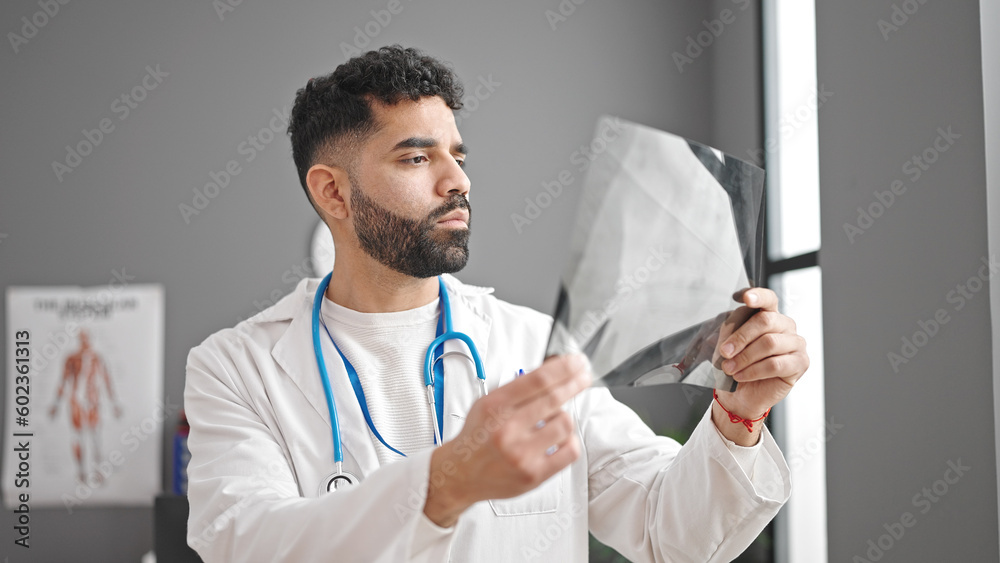 Young hispanic man doctor looking xray at clinic Young hispanic man doctor looking xray at clinic