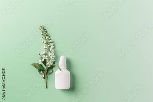 Seasonal allergy concept, spring blooming branches tree and mock up nasal spray white bottle on gradient green background, copyspace, top view, Healthy lifestyle, treatment seasonal allergies photo