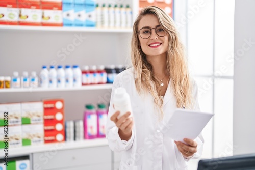 Free Download Young woman pharmacist reading prescription holding pills bottle at pharmacy - GFXLoad