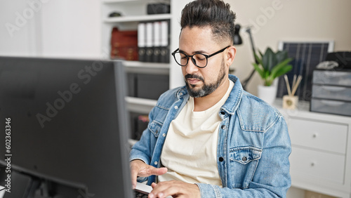 Young latin man business worker using computer working at office