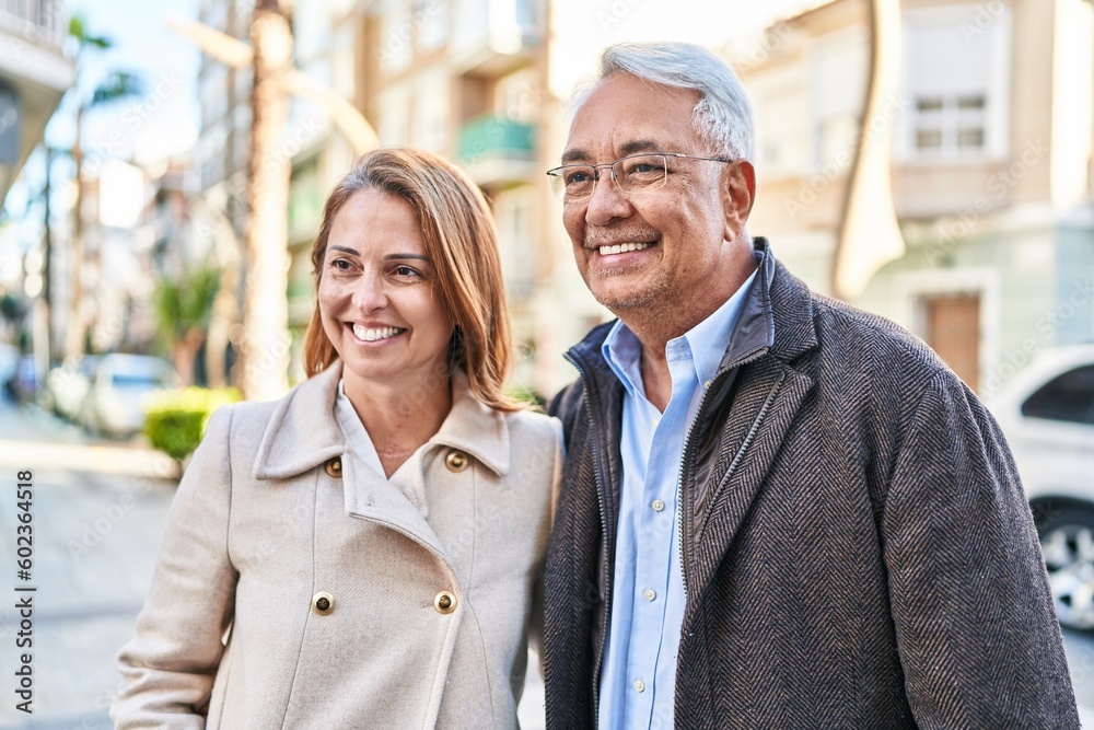 Middle age man and woman couple hugging each other standing at street Middle age man and woman couple hugging each other standing at street