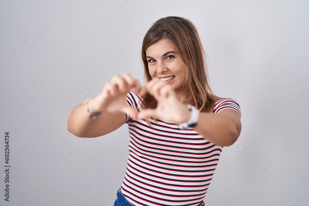Young hispanic woman standing over isolated background smiling in love doing heart symbol shape with hands. romantic concept. Young hispanic woman standing over isolated background smiling in love doing heart symbol shape with hands. romantic concept.