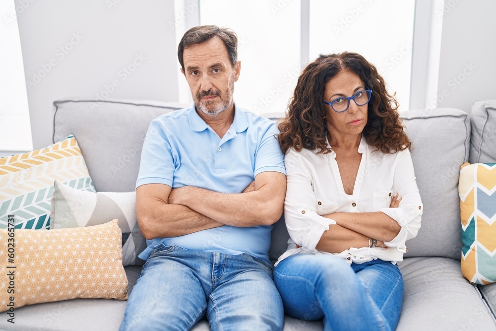 Man and woman couple sitting on sofa with serious expression at home Man and woman couple sitting on sofa with serious expression at home