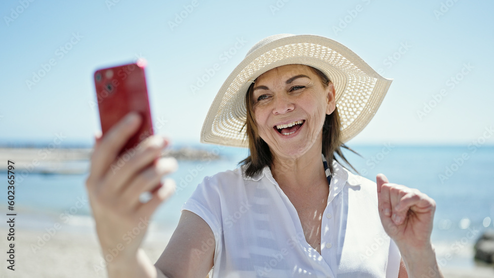 Fototapeta premium Middle age hispanic woman tourist smiling confident make selfie with smartphone at the beach