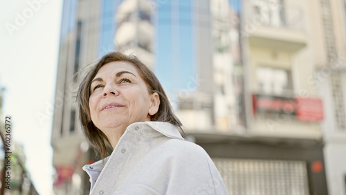 Middle age hispanic woman smiling confident looking at the sky at street