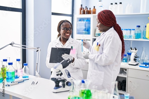 African american women scientist holding test tube writing on document at laboratory © Krakenimages.com