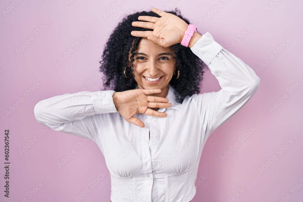 Hispanic woman with curly hair standing over pink background smiling cheerful playing peek a boo with hands showing face. surprised and exited Hispanic woman with curly hair standing over pink background smiling cheerful playing peek a boo with hands showing face. surprised and exited