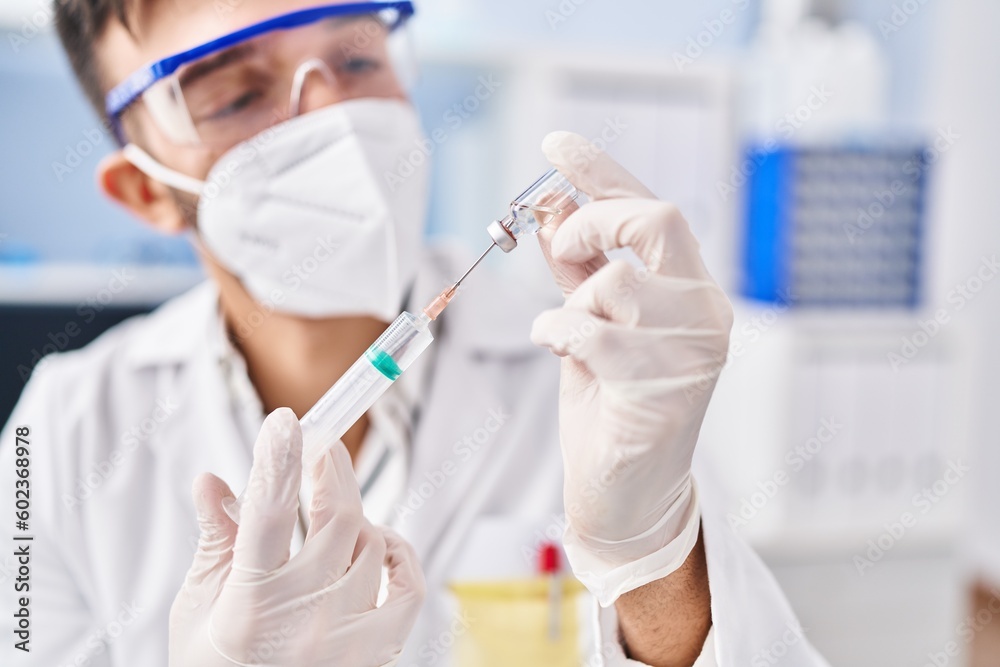 Young hispanic man scientist wearing medical mask holding covid vaccine at laboratory