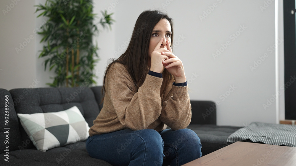 Beautiful hispanic woman sitting on sofa with doubt expression at home Beautiful hispanic woman sitting on sofa with doubt expression at home