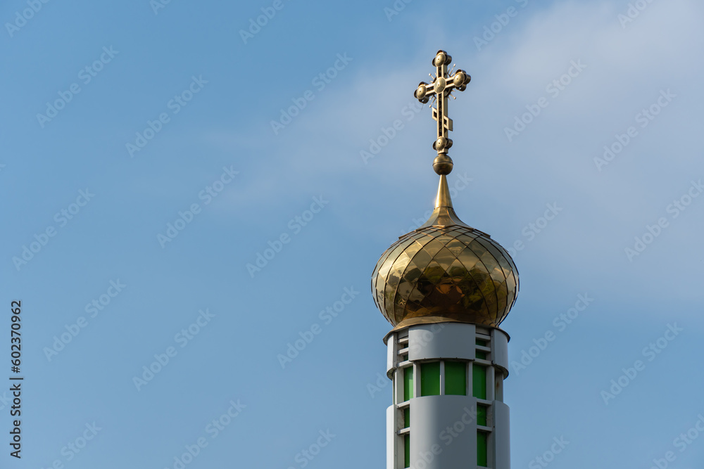 Tower with large golden dome and cross against blue sky. Place religion of orthodox christian for prayer in modern city. Monastyrsky island with church of saint Nicholas in Dnipro Ukraine. Bottom view