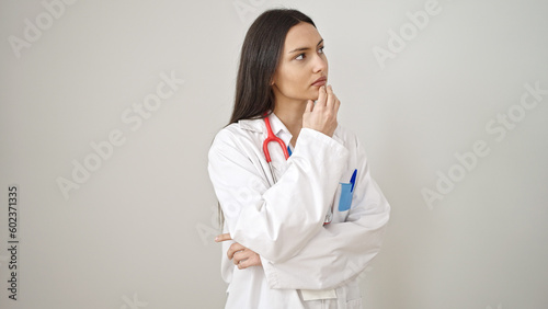 Young beautiful hispanic woman doctor standing with doubt expression thinking over isolated white background