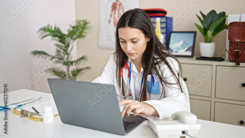 Young beautiful hispanic woman doctor using laptop working at clinic