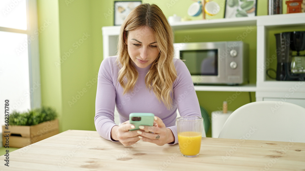 Young beautiful hispanic woman using smartphone sitting on the table at dinning room Young beautiful hispanic woman using smartphone sitting on the table at dinning room