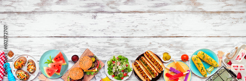 Summer BBQ food bottom border. Hamburgers, hot dogs, potatoes, corn and cold treats. Top down view over a white wood banner background. Copy space.