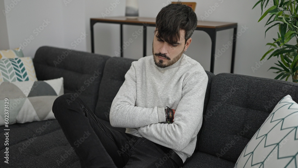 Young hispanic man sitting on the sofa upset with crossed arms at home Young hispanic man sitting on the sofa upset with crossed arms at home