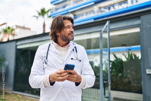 Middle age man doctor smiling confident using smartphone at hospital © Krakenimages.com