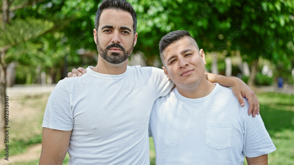 Two men hugging each other with relaxed expression at park