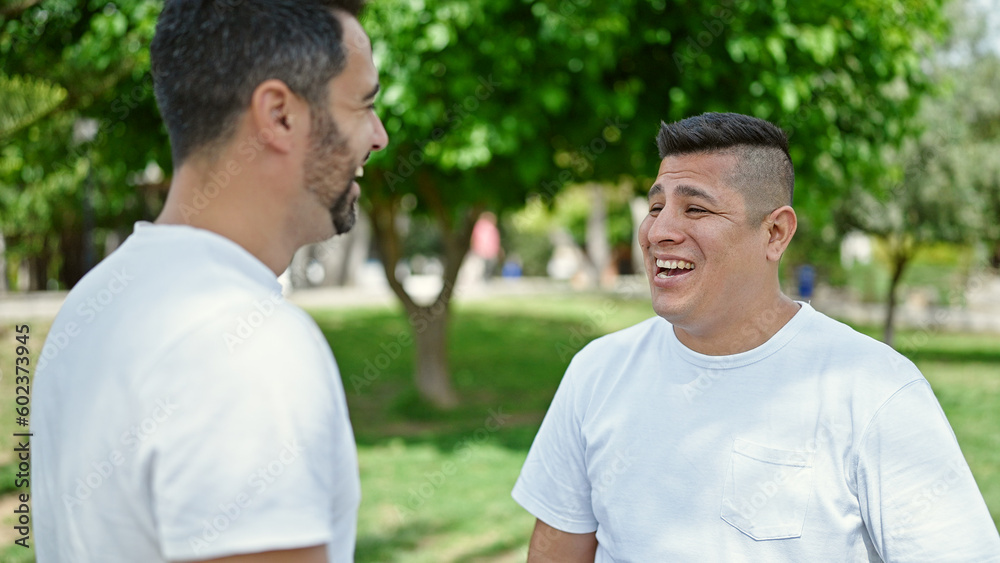 Two men standgin together speaking at park Two men standgin together speaking at park