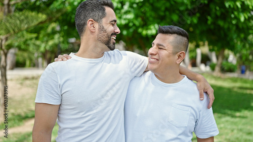 Two men smiling confident hugging each other at park