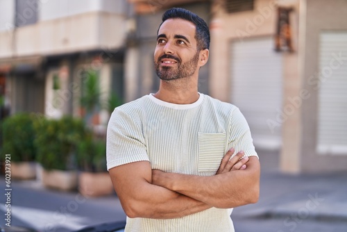 Young hispanic man smiling confident standing with arms crossed gesture at street