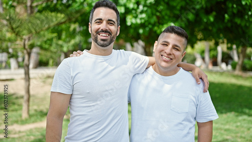 Two men smiling confident hugging each other at park
