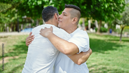 Two men hugging each other with relaxed expression at park