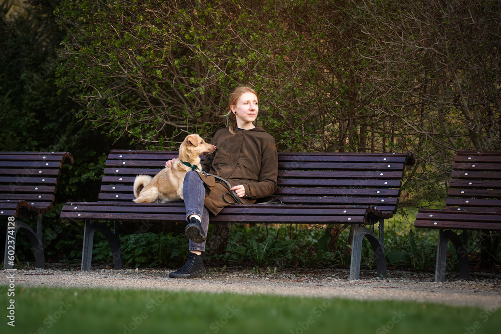 Beautiful blonde girl with dog walking in the park