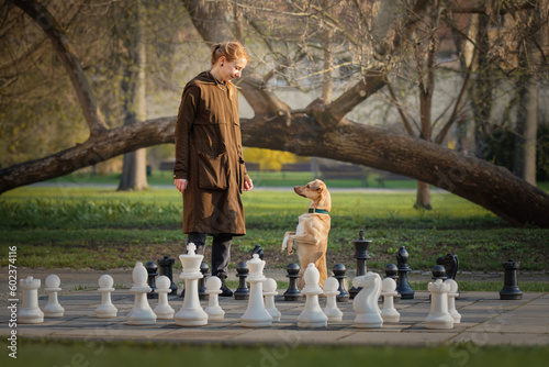 Obraz na płótnie Beautiful girl and little red dog and big chess w salonie