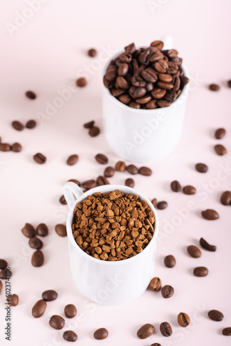Choice between instant coffee and roasted coffee beans in cups on pink background vertical view
