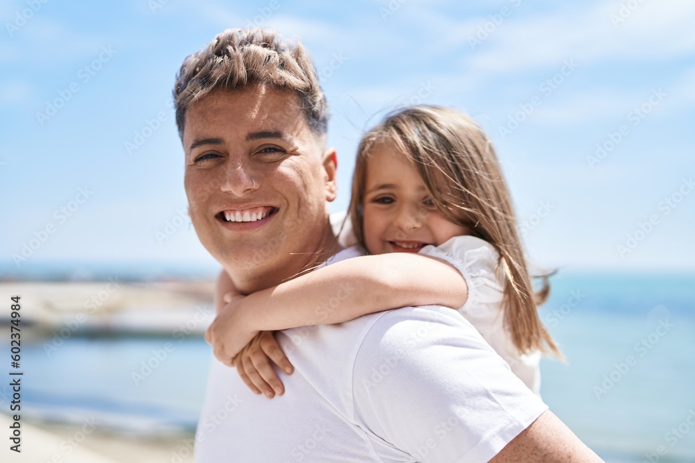 Father and daughter smiling confident hugging each other holding on back at seaside Father and daughter smiling confident hugging each other holding on back at seaside