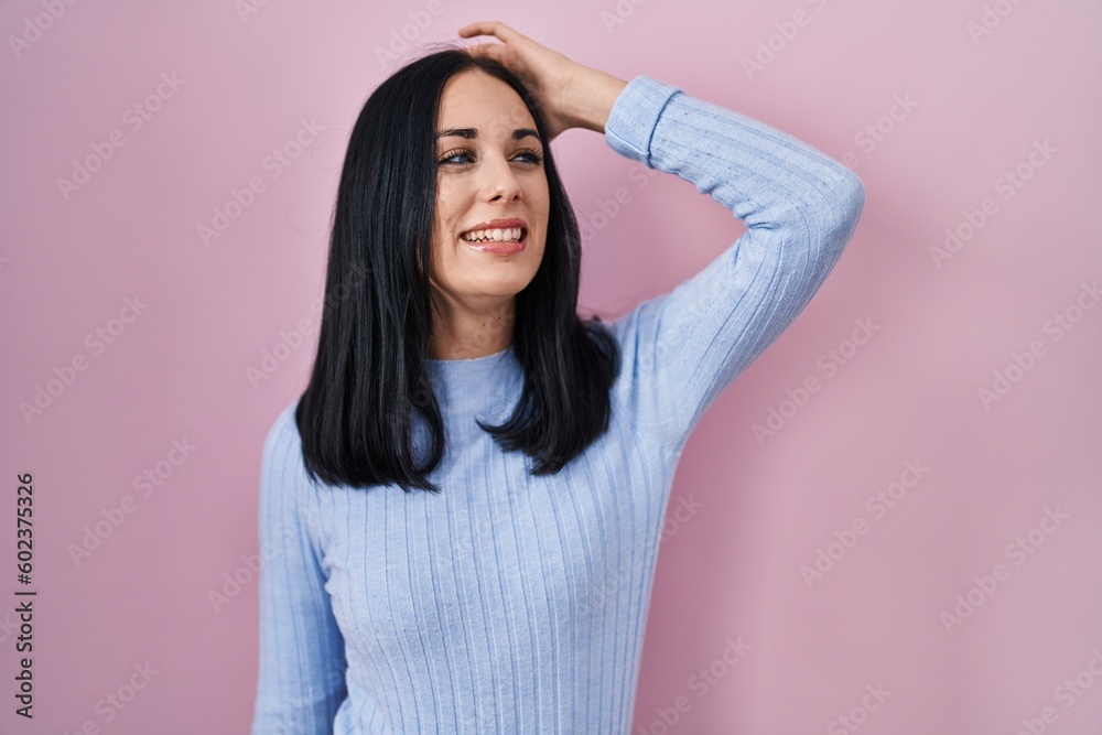 Hispanic woman standing over pink background smiling confident touching hair with hand up gesture, posing attractive and fashionable Hispanic woman standing over pink background smiling confident touching hair with hand up gesture, posing attractive and fashionable