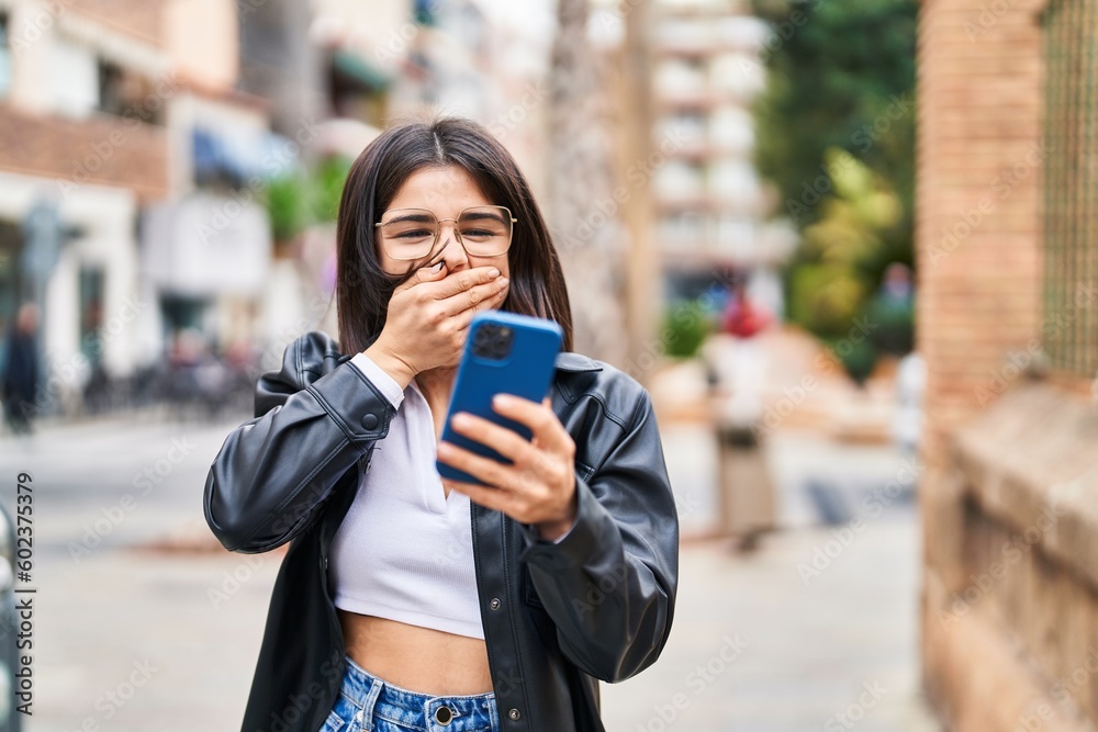 Young beautiful hispanic woman using smartphone with surprise expression at street