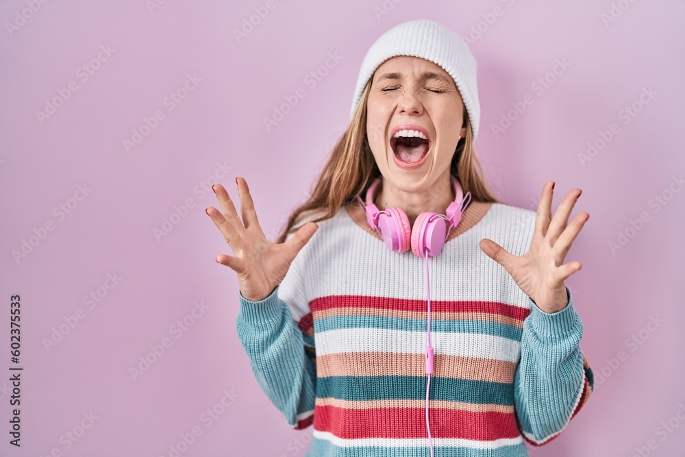 Young blonde woman standing over pink background celebrating mad and crazy for success with arms raised and closed eyes screaming excited. winner concept