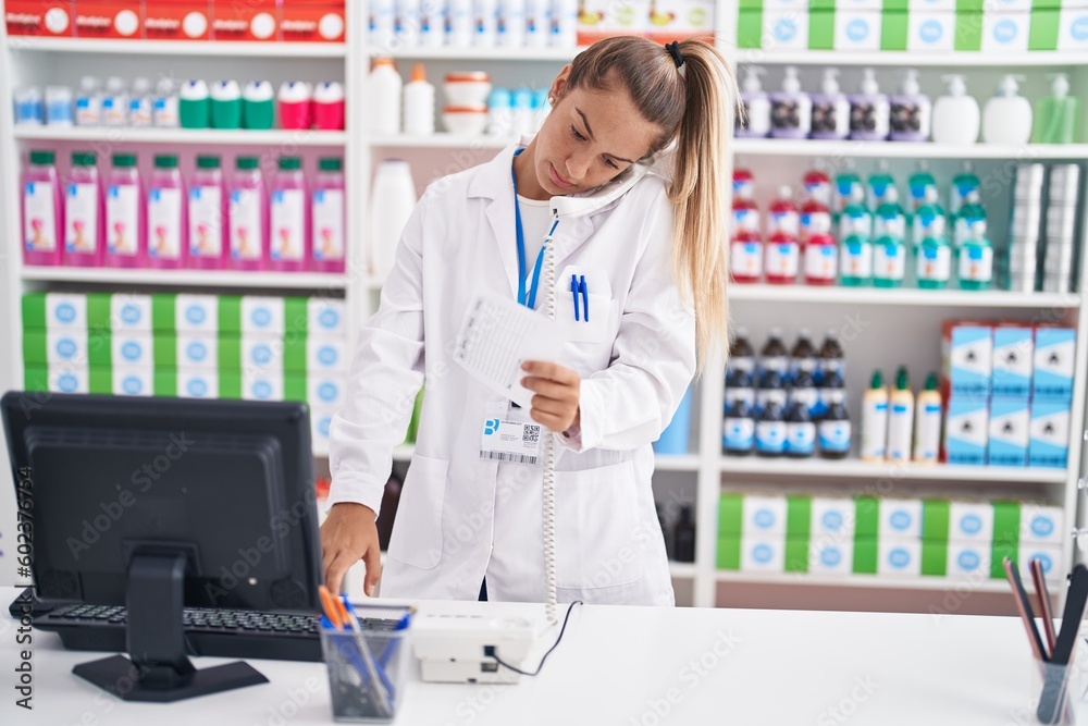 Young beautiful hispanic woman pharmacist talking on telephone reading prescription paper at pharmacy