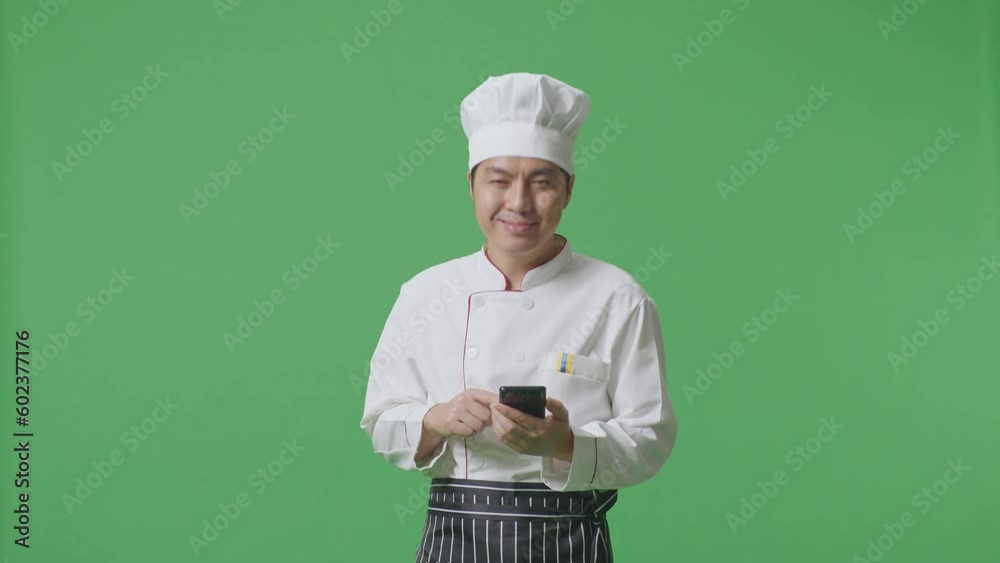 Asian Man Chef Smiling And Pointing To Smartphone In His Hand While Standing In The Green Screen Background Studio
Asian Man Chef Smiling And Pointing To Smartphone In His Hand While Standing In The Green Screen Background Studio
