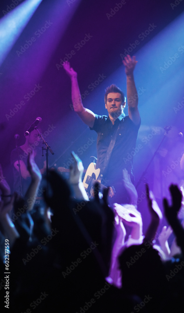 People hands, music and singer at concert in night performance, rock band or gen z in neon lights or cheers. Musician man on stage at disco event and fans clapping, crowd or audience dancing on floor