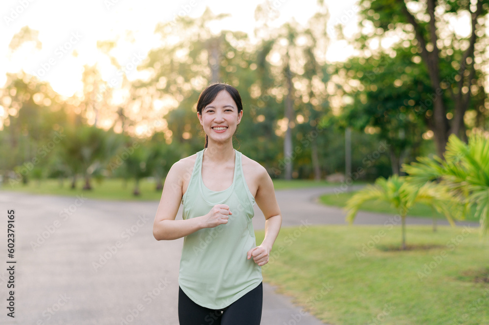Fit Asian young woman jogging in park smiling happy running and enjoying a healthy outdoor lifestyle. Female jogger. Fitness runner girl in public park. healthy lifestyle and wellness being concept Fit Asian young woman jogging in park smiling happy running and enjoying a healthy outdoor lifestyle. Female jogger. Fitness runner girl in public park. healthy lifestyle and wellness being concept
