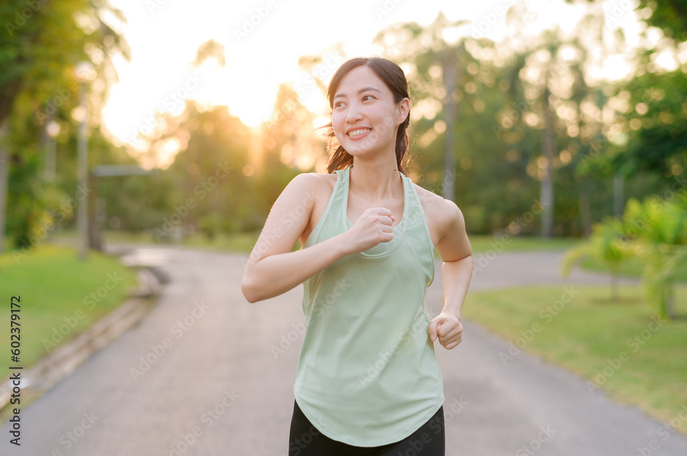 Fit Asian young woman jogging in park smiling happy running and enjoying a healthy outdoor lifestyle. Female jogger. Fitness runner girl in public park. healthy lifestyle and wellness being concept Fit Asian young woman jogging in park smiling happy running and enjoying a healthy outdoor lifestyle. Female jogger. Fitness runner girl in public park. healthy lifestyle and wellness being concept