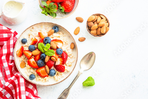 Oatmeal porrige with fresh berries and nuts. Healthy breakfast, top view.
