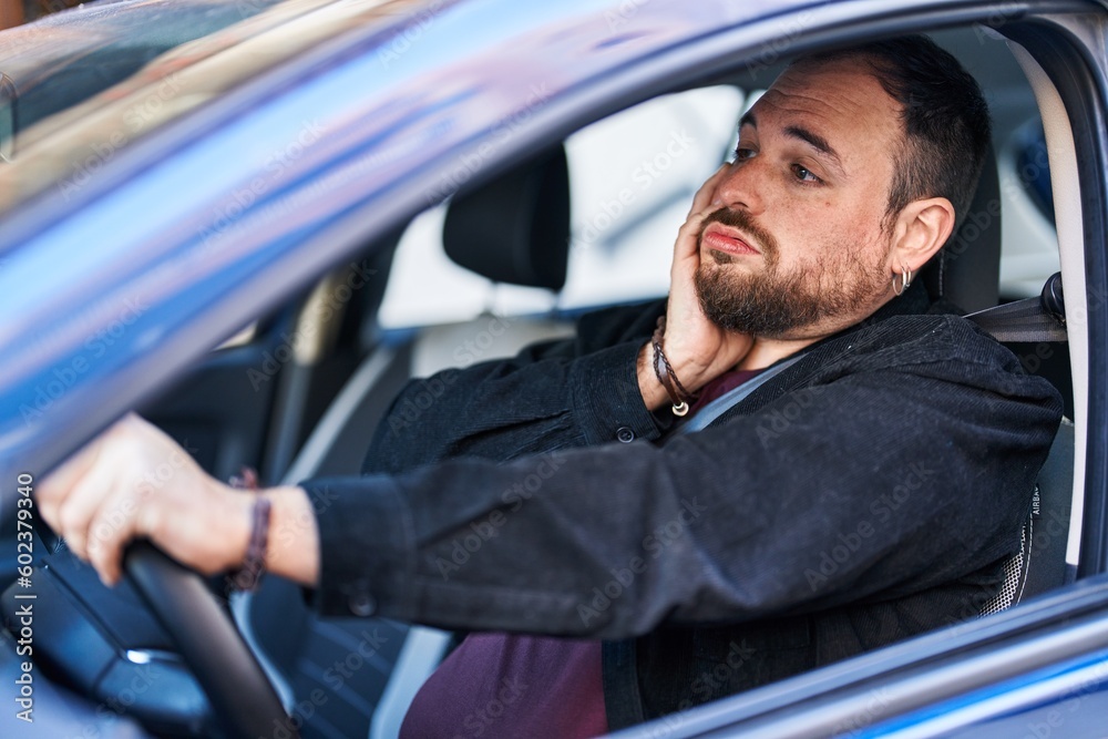 Young hispanic man driving car with desperate expression at street