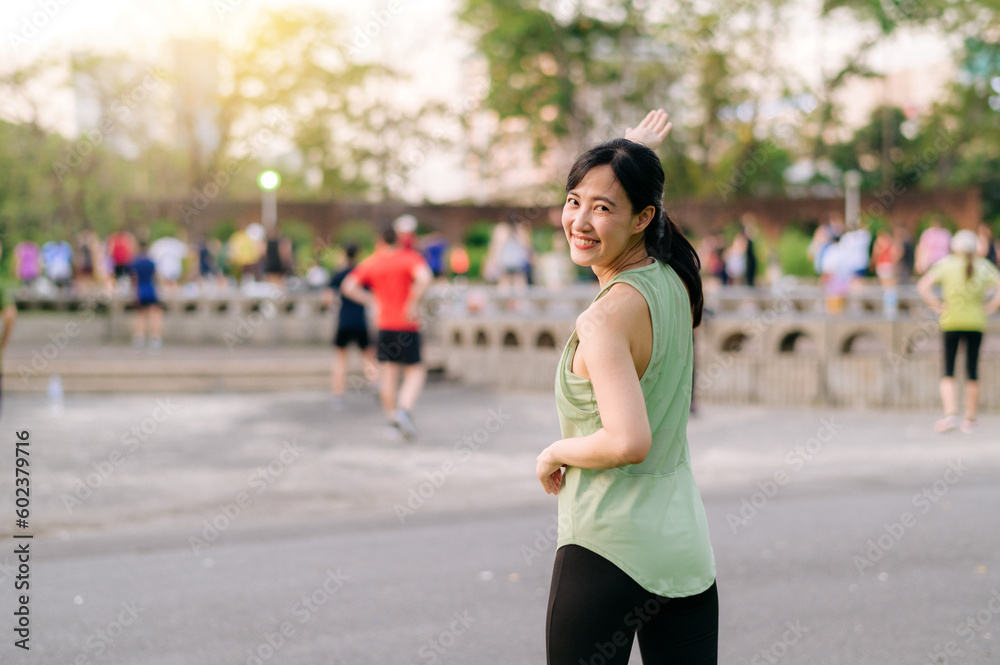 Female jogger. Fit young Asian woman with green sportswear aerobics dance exercise in park and enjoying a healthy outdoor. Fitness runner girl in public park. Wellness being concept