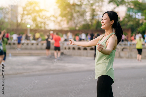 Female jogger. Fit young Asian woman with green sportswear aerobics dance exercise in park and enjoying a healthy outdoor. Fitness runner girl in public park. Wellness being concept