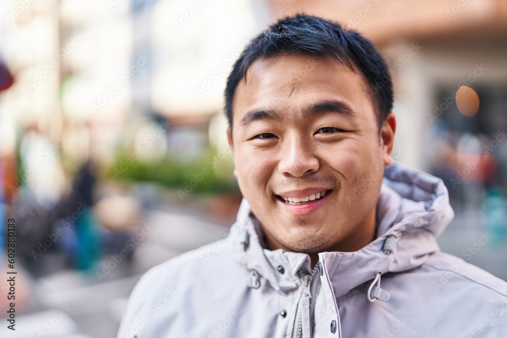 Fototapeta premium Young chinese man smiling confident standing at street