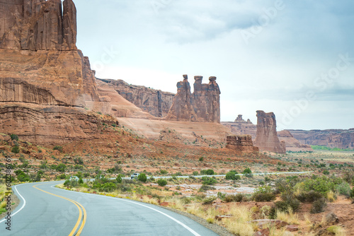 road leading to sandstone three sisters rock formation at arches national park