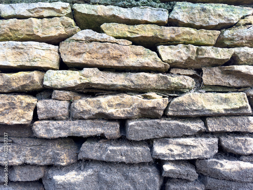 Cobblestone wall, old stone masonry rough texture ancient wall. Grunge natural real rock  stone wall background, close up, detail.