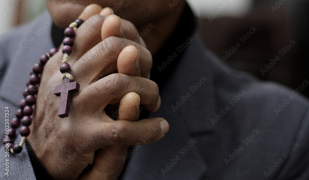man praying to god with hands together Caribbean man praying with grey background stock photos stock photo